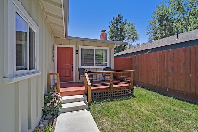 property entrance with a lawn and a wooden deck