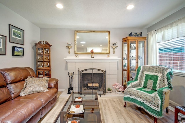 living area featuring hardwood / wood-style flooring, a textured ceiling, and a tile fireplace