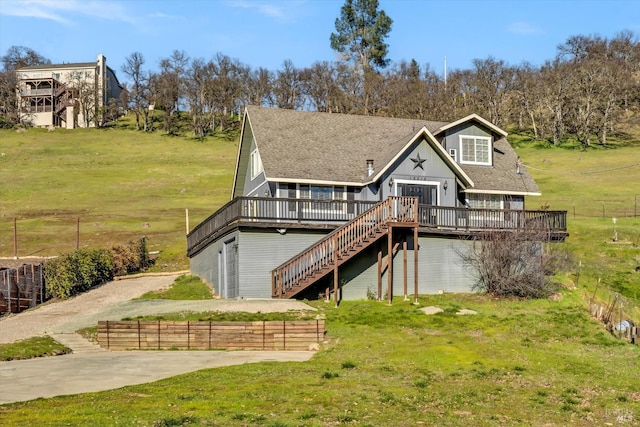 rear view of property with a wooden deck, a lawn, and a rural view