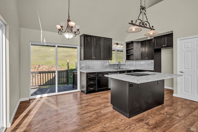 kitchen featuring lofted ceiling, a center island, pendant lighting, black electric stovetop, and backsplash