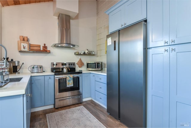 kitchen featuring dark wood-type flooring, light countertops, appliances with stainless steel finishes, wall chimney exhaust hood, and open shelves