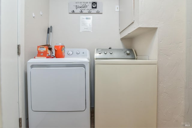 clothes washing area with cabinets and washer and dryer