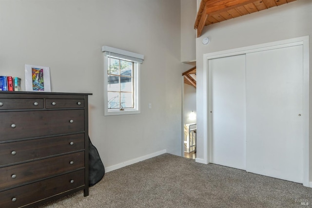 bedroom featuring a closet, carpet flooring, baseboards, and beam ceiling