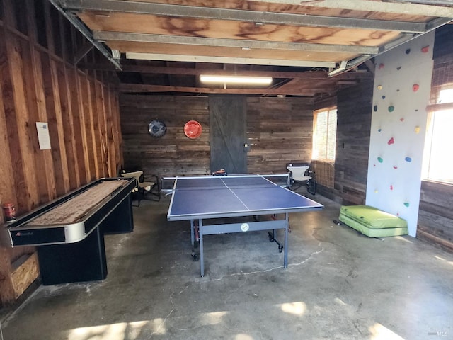 game room featuring wooden walls and concrete floors