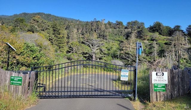 view of gate with a wooded view and fence