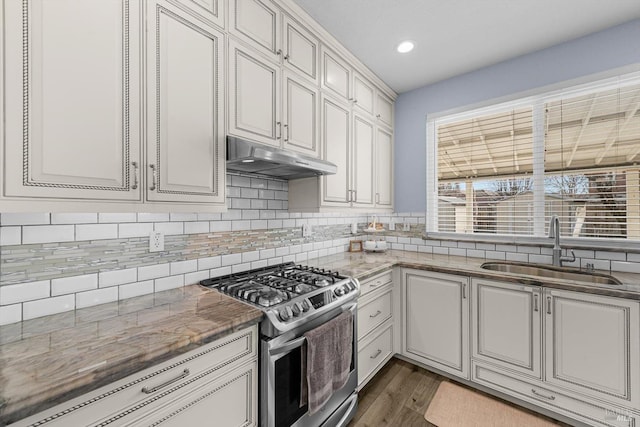 kitchen featuring gas range, sink, white cabinets, light stone counters, and dark hardwood / wood-style floors