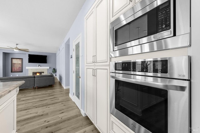 kitchen with ceiling fan, white cabinetry, light hardwood / wood-style flooring, and stainless steel appliances