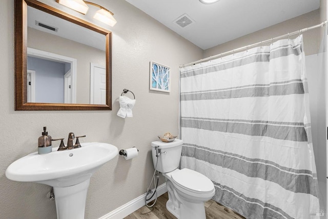 bathroom featuring hardwood / wood-style flooring, toilet, and walk in shower