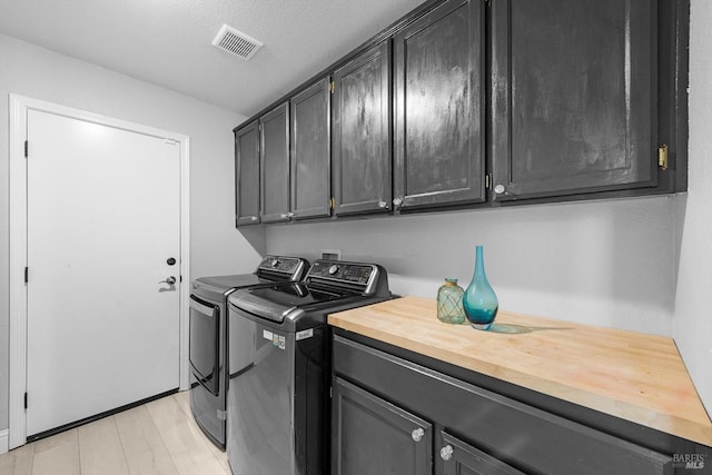 laundry area with cabinets, a textured ceiling, and separate washer and dryer