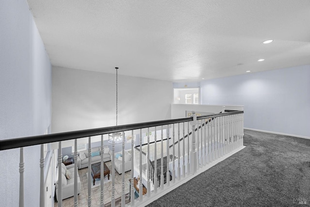 corridor featuring a textured ceiling and carpet floors