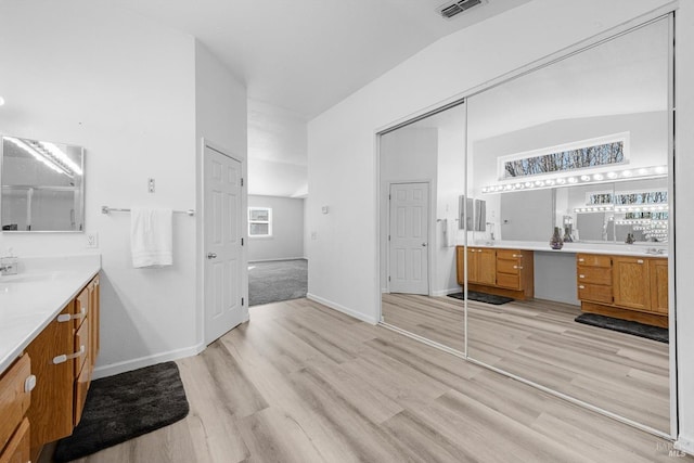 bathroom with vanity, wood-type flooring, and lofted ceiling