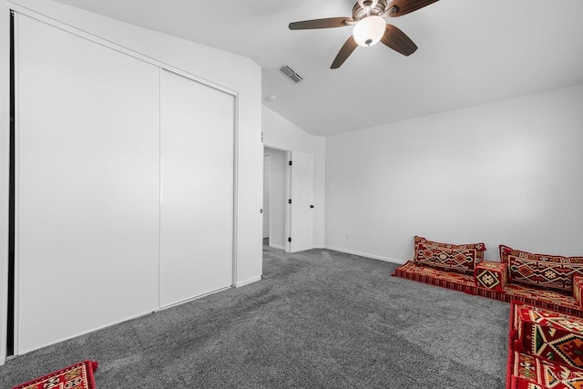 interior space with ceiling fan, dark carpet, and lofted ceiling