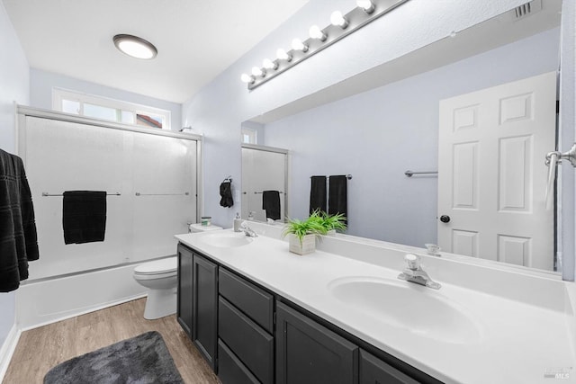 full bathroom with vanity, toilet, combined bath / shower with glass door, and hardwood / wood-style floors