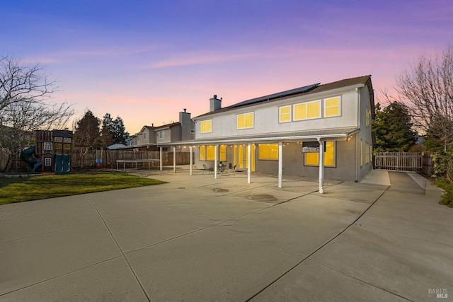 back house at dusk with a playground and a patio area