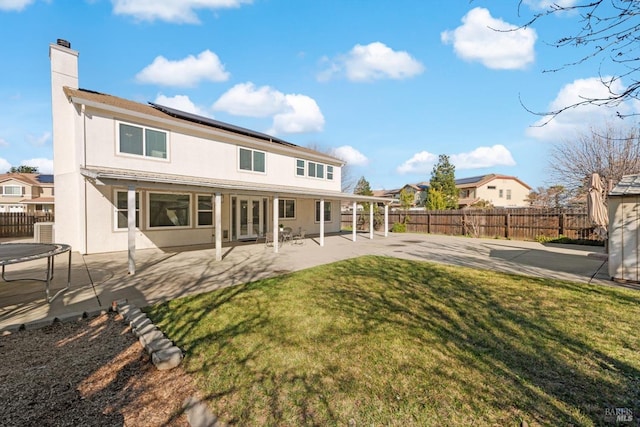 rear view of property featuring a patio, a trampoline, central AC unit, and a yard