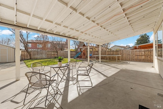 view of patio / terrace featuring a playground, a trampoline, and a storage unit