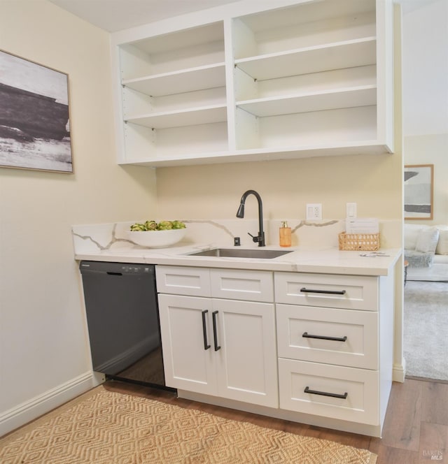 bar featuring sink, light hardwood / wood-style flooring, black dishwasher, light stone countertops, and white cabinets