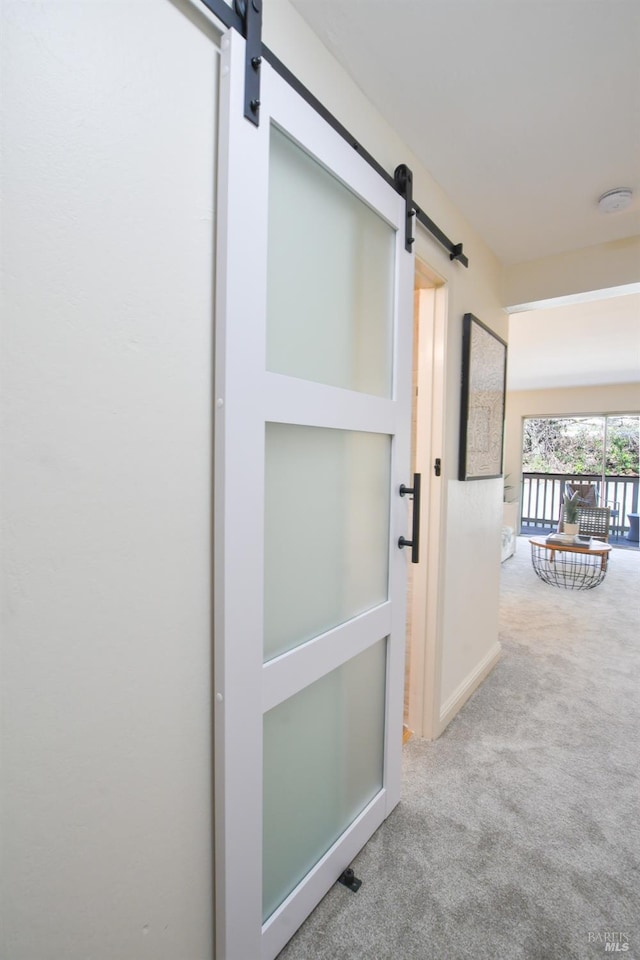 corridor featuring a barn door and light carpet