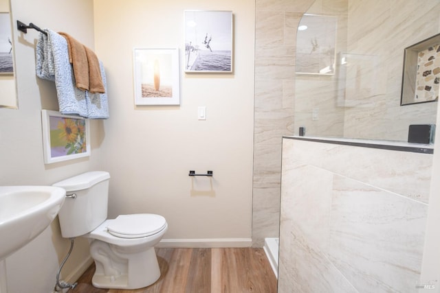 bathroom featuring a tile shower, hardwood / wood-style floors, and toilet