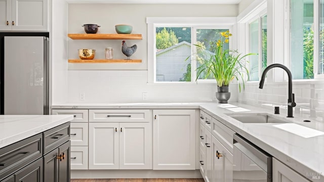 kitchen featuring light stone countertops, dishwashing machine, white cabinets, white fridge, and sink