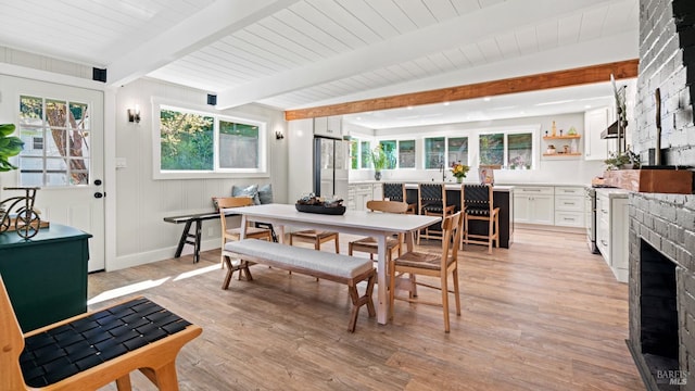 dining area with a fireplace, wooden ceiling, light wood-type flooring, and beam ceiling