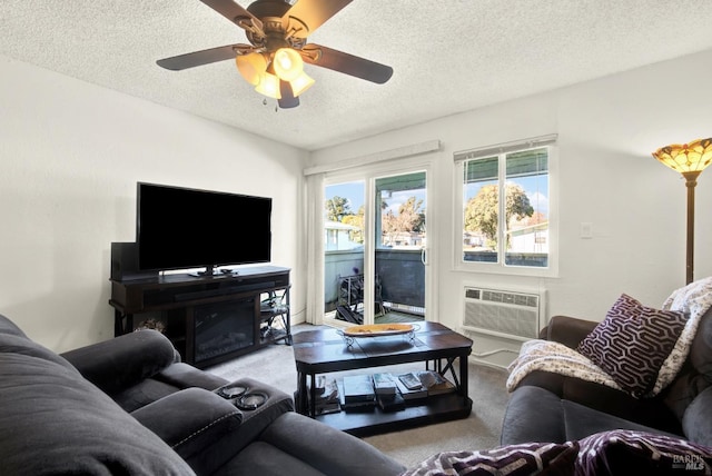 living room featuring a wall mounted air conditioner, ceiling fan, light colored carpet, and a textured ceiling