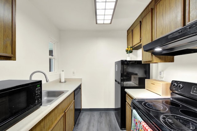 kitchen with sink, black appliances, dark hardwood / wood-style floors, and wall chimney range hood