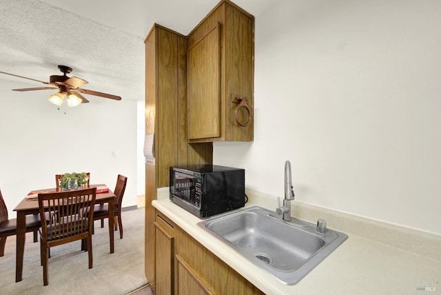 kitchen with ceiling fan, sink, a textured ceiling, and light colored carpet