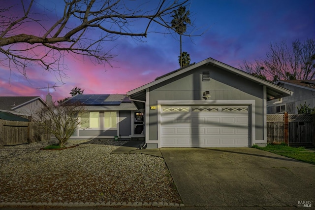 ranch-style house featuring a garage and solar panels