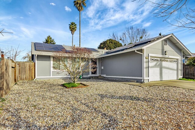 single story home with a garage and solar panels