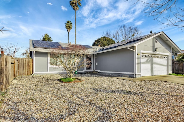 ranch-style house featuring a garage and solar panels