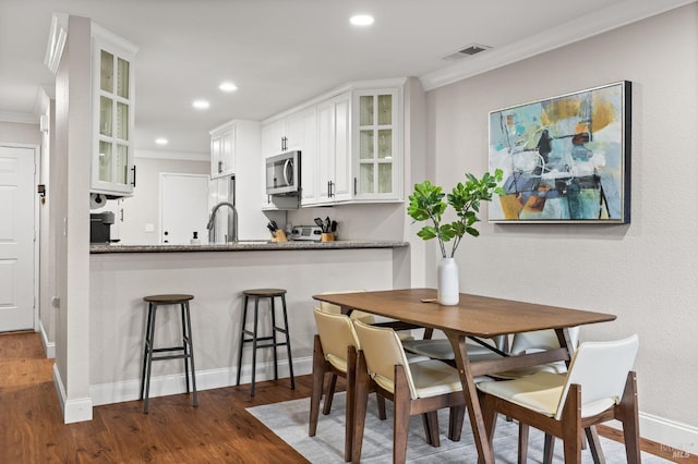 dining area featuring dark wood-type flooring and ornamental molding