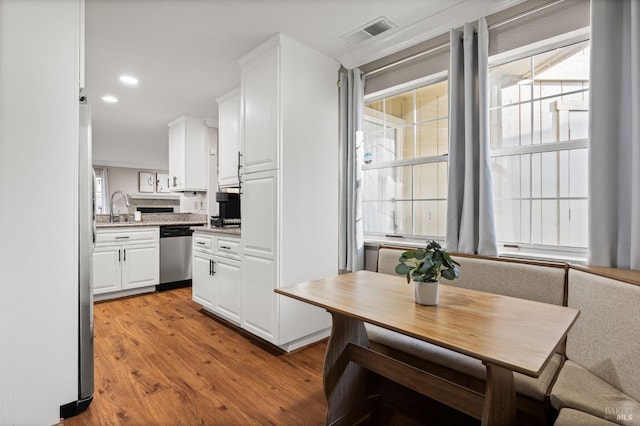 kitchen featuring sink, light wood-type flooring, breakfast area, stainless steel appliances, and white cabinets