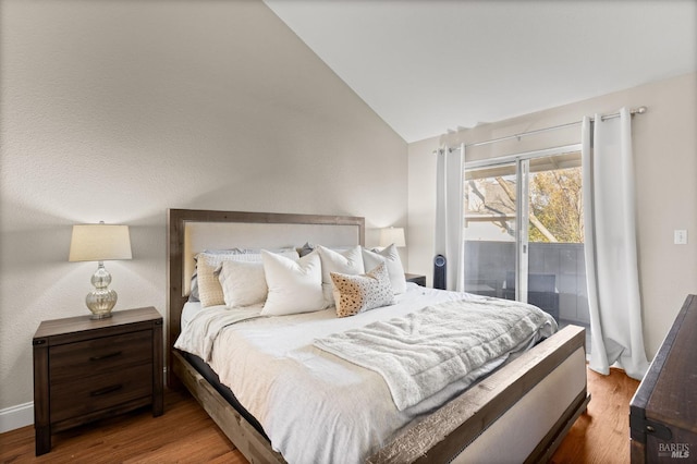 bedroom featuring lofted ceiling, access to exterior, and hardwood / wood-style floors