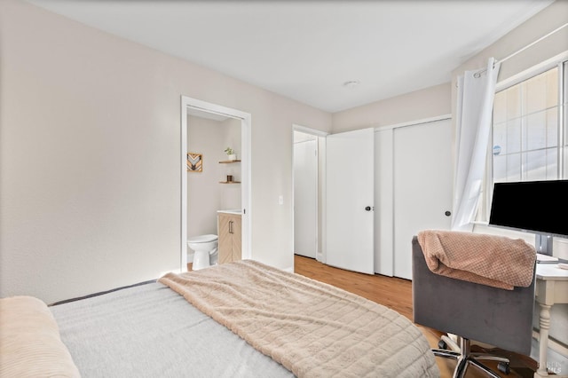 bedroom featuring a closet, ensuite bathroom, and light hardwood / wood-style flooring