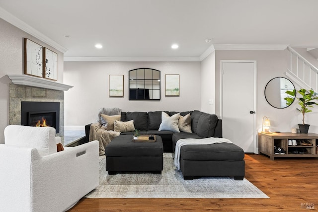 living room featuring a tile fireplace, ornamental molding, and hardwood / wood-style floors