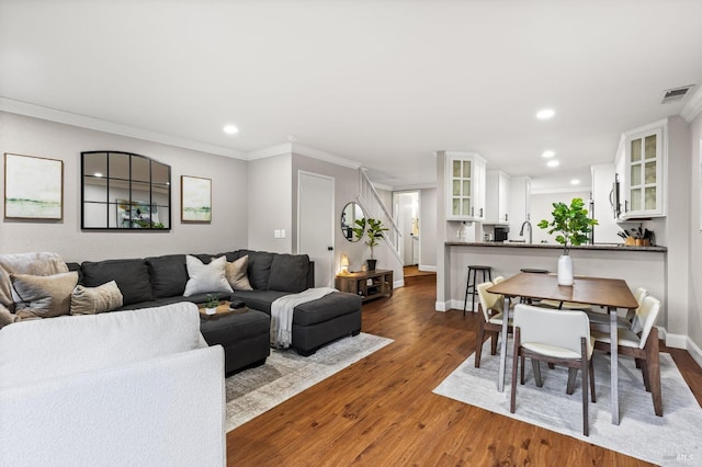 living room featuring hardwood / wood-style flooring, ornamental molding, and sink