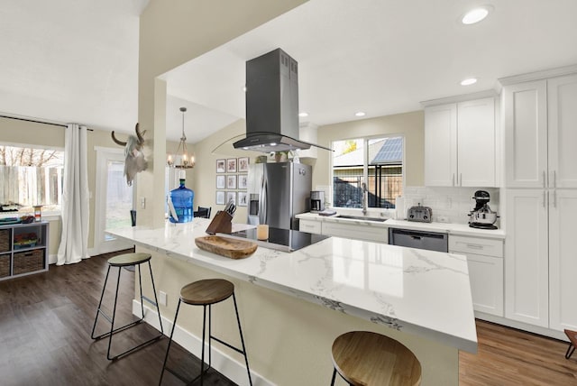 kitchen featuring white cabinetry, a center island, appliances with stainless steel finishes, a kitchen bar, and island range hood