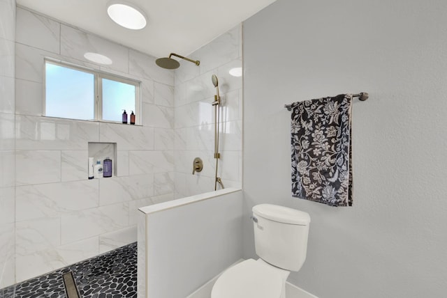 bathroom featuring tiled shower and toilet