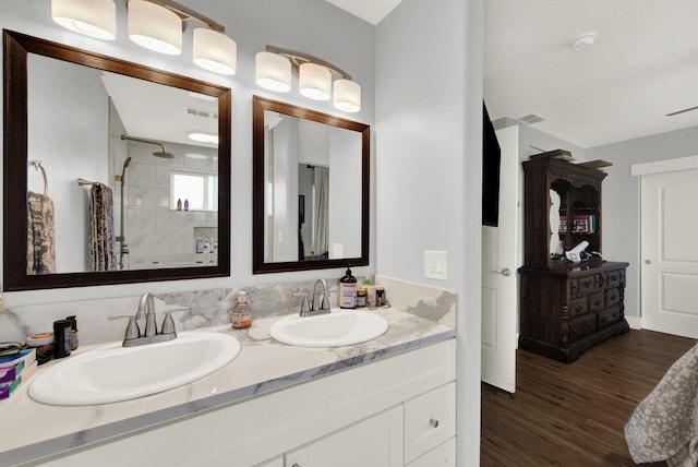 bathroom with vanity, tiled shower, and wood-type flooring