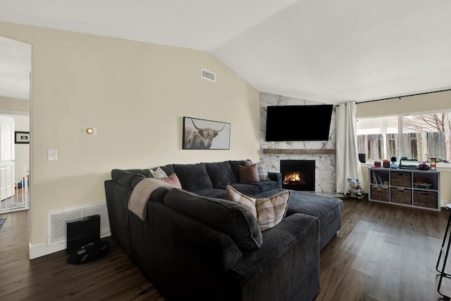 living room featuring a premium fireplace, lofted ceiling, and dark wood-type flooring