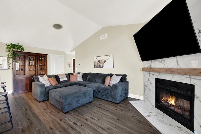 living room featuring vaulted ceiling, a premium fireplace, and hardwood / wood-style flooring