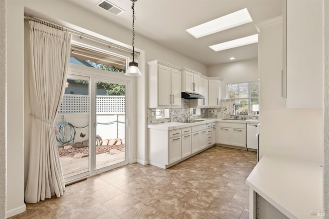 kitchen featuring plenty of natural light, a skylight, hanging light fixtures, and white cabinets