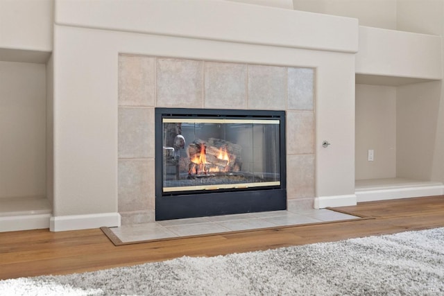 room details with a tiled fireplace and hardwood / wood-style floors