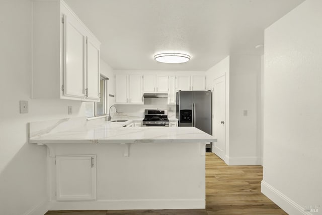 kitchen featuring sink, appliances with stainless steel finishes, kitchen peninsula, light hardwood / wood-style floors, and white cabinets