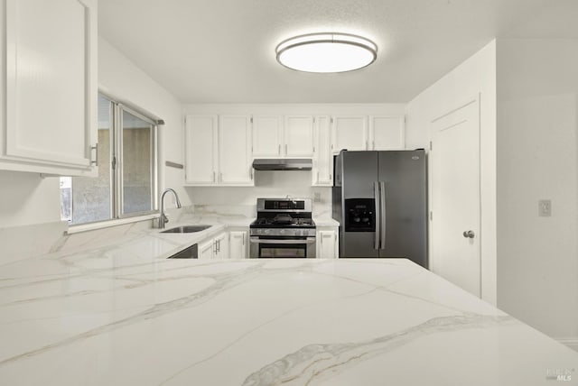 kitchen with light stone countertops, appliances with stainless steel finishes, sink, and white cabinets