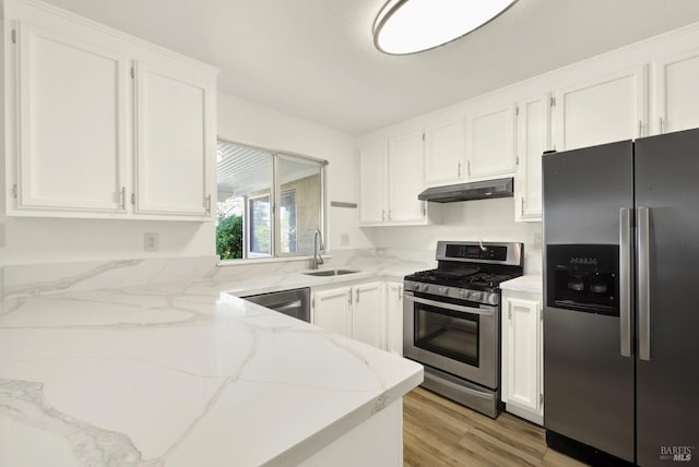 kitchen with sink, white cabinetry, appliances with stainless steel finishes, light stone countertops, and light hardwood / wood-style floors