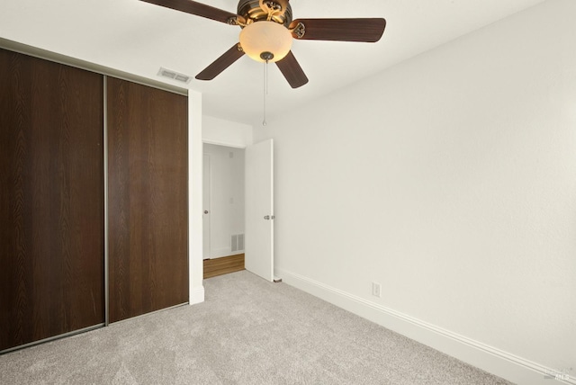 unfurnished bedroom featuring light carpet, ceiling fan, and a closet