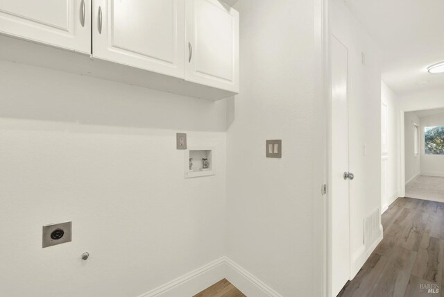 clothes washing area featuring dark wood-type flooring, cabinets, hookup for an electric dryer, and hookup for a washing machine