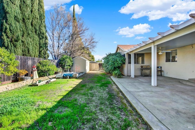 view of yard with ceiling fan, a shed, and a patio area